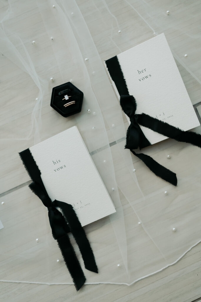 Modern wedding detail photos of the bride's rings and matching vow books.