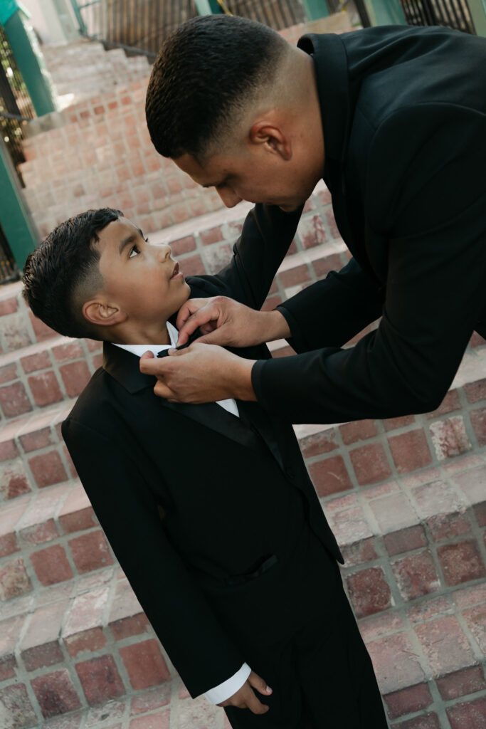 Groom and son getting ready in a modern all black tux for his wedding in Arizona.