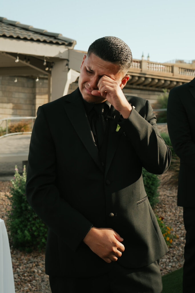 Groom's reaction to seeing bride walk down the aisle for the first time at her modern and minimal wedding in Arizona.