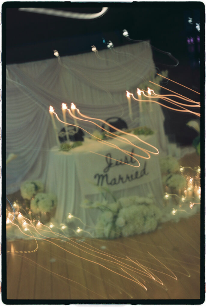 Double exposure film photograph of a “Just Married” sign layered with white florals and champagne glasses at a modern Arizona wedding.